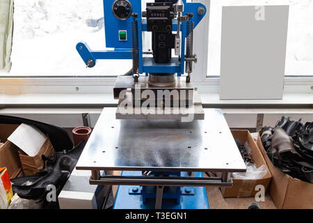 Premere la macchina in officina per fare il logo in rilievo e lettere sul manufatto in pelle che riscalda il cliché e spreme l'immagine desiderata su t Foto Stock