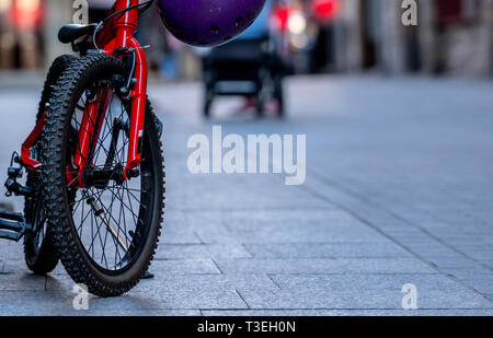 Chiudere i bambini noleggio parcheggiato sulla strada in città. Red bicicletta con ruote nere. Il Kid's bicicletta. Foto Stock