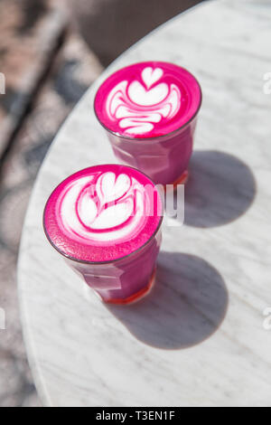 Due colorato di rosa alla moda barbabietole latte sul pavimento di marmo bianco dello sfondo. Foto Stock