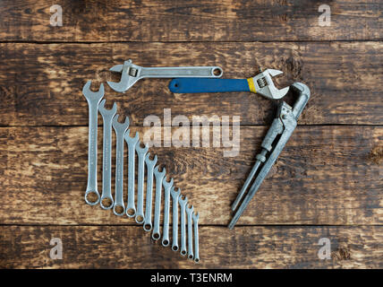Set di chiavi a combinazione e vecchie chiavi regolabili su un vecchio di tavole di legno sfondo Foto Stock