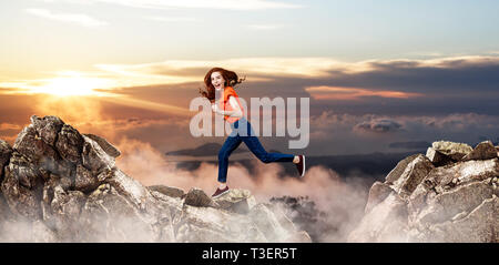 Redhead donna salta alla scogliera sul cielo blu sullo sfondo. Foto Stock