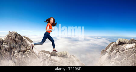 Redhead donna salta alla scogliera sul cielo blu sullo sfondo. Foto Stock