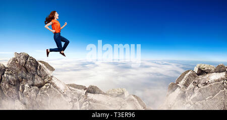 Redhead donna salta alla scogliera sul cielo blu sullo sfondo. Foto Stock