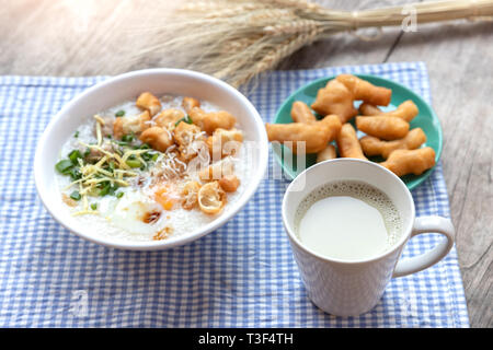 Breakfase pasto. Congee o riso porridge di carne macinata di maiale, uovo sodo con latte di soia e il cinese fritte doppio bastone di pasta Foto Stock