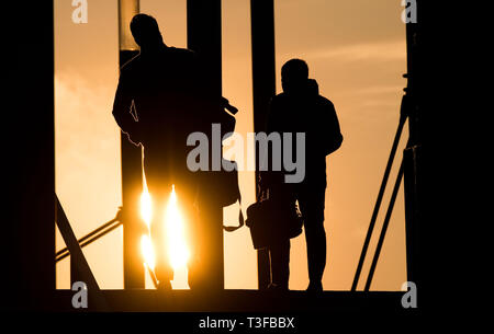 Hannover, Germania. 09Apr, 2019. Due uomini a piedi nella valigetta al tramonto su un ponte a Expo Plaza. Credito: Julian Stratenschulte/dpa/Alamy Live News Foto Stock