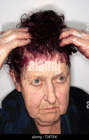 82-anno vecchia donna applicando tintura per capelli Foto Stock