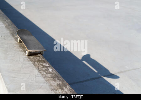 Professional skateboard posa sulla mensola di calcestruzzo a skate park. Pratica freestyle, urban sport estremo attività per la gioventù, tenersi fuori dai guai Foto Stock