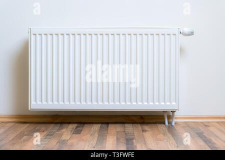 Home Radiatore riscaldatore sul muro bianco sul legno del pavimento di legno duro. Riscaldamento regolabile attrezzatura per appartamento e home Foto Stock