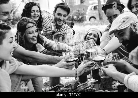 Gruppo di persone il tifo con red bicchieri di vino - Happy giovani amici godendo picnic in un parco con cibi e bevande - bianco e nero modifica Foto Stock