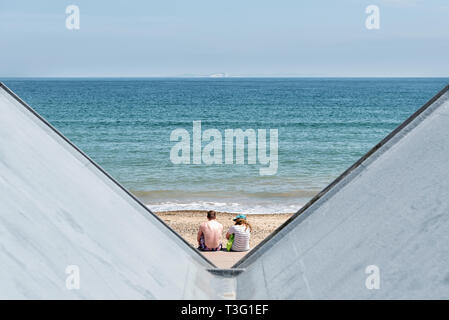 Due persone sulla spiaggia con il tetto di spiaggia capanne in primo piano Foto Stock