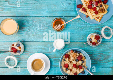 Tavolo per la colazione con cialde, fiocchi d'avena, cereali, caffè, succo di frutta e frutti di bosco freschi