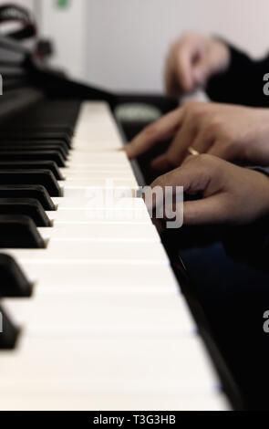 Piccole e grandi mani sulla tastiera del pianoforte senza facce. Foto Stock