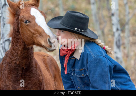 Cowgirl kiss con giovani colt Foto Stock