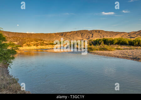 Rio Grande, luna su montagne in Messico in distanza, vista da Talley campeggio, al tramonto, Mariscal area del Canyon, il Parco nazionale di Big Bend, Texas, Stati Uniti d'America Foto Stock