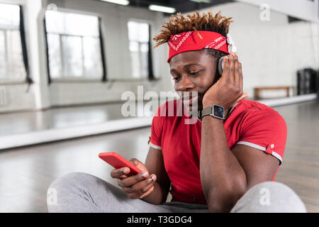 Piacevole sorridente a pelo corto guy ascoltando la musica attraverso le cuffie Foto Stock