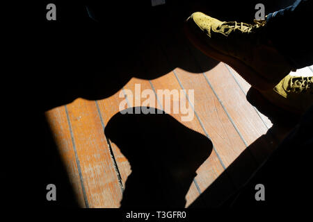 Suede sneakers creative con le ombre in esterni con pavimento in legno duro e copia dello spazio. Foto Stock