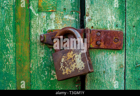 Rusty la cerniera dello sportello a e vecchia serratura su legno verde porta con incrinato e gratta e vinci. Orizzontale texture grunge. Foto Stock