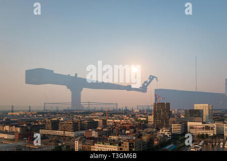 La riflessione di una gru su una parte anteriore in vetro al paesaggio cittadino di Anversa, Belgio Foto Stock