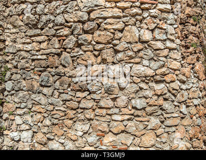 La texture del vecchio muro di pietra. Superficie dal grigio e arancione pietre. Antico muro in Macedonia. Foto Stock