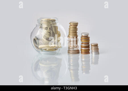 Pile di monete metalliche e le banconote di dollari su un tavolo bianco. Il concetto di business Foto Stock