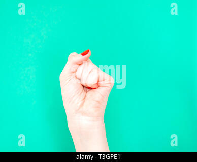 La donna la mano con il pugno chiuso sulla isolato verde turchese colore di sfondo. Foto Stock