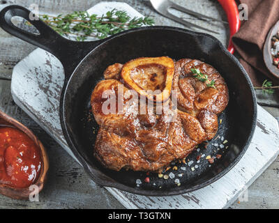 Osso Buco cucinato Stinco di vitello su una porzione padella di ferro, salsa rossa, spezie Foto Stock