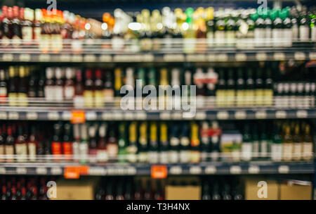 Immagine sfocata di liquore di vino Bottiglie sul ripiano in un supermercato. Ripiano sfocati con bottiglie di vino nel supermercato Foto Stock