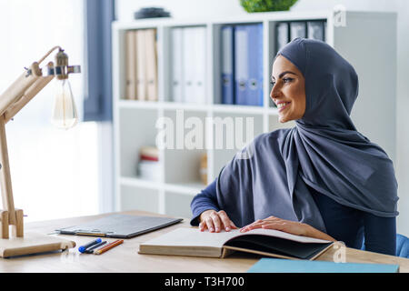 Felice donna seduta nel suo ufficio Foto Stock