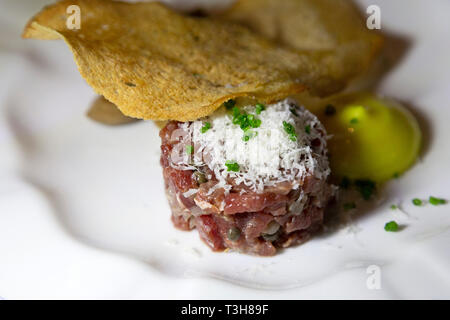 Tartare di manzo servita con una sottile fetta di pane croccante. La carne cruda viene rabboccato con formaggio grattugiato. Foto Stock