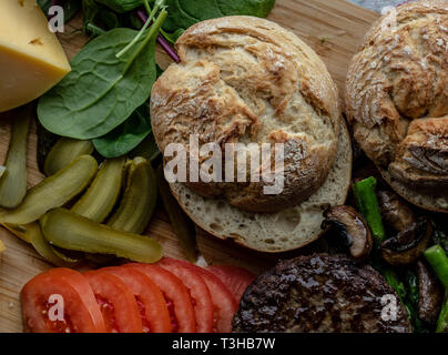 Cotto al forno funghi champignon burger con aggiunta di lattuga fresca, pomodoro, asparagi e fresche foglie di spinaci Foto Stock