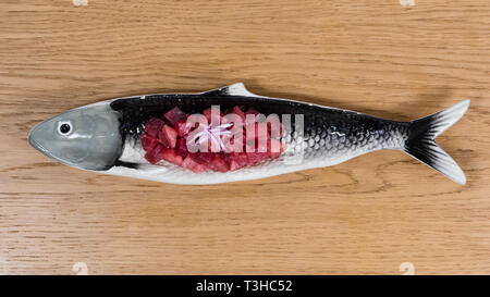 Il tonno rosso tartare di tonno con un trito di cipolla rossa, servita su un pesce a forma di lastra Foto Stock