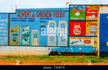 Una parete visualizzando un dipinto di pubblicità per mangimi per polli e cemento a Lilongwe Malawi Foto Stock
