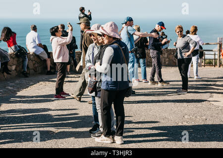 Il Portogallo, Sintra, 26 Giugno 2018: donne asiatiche i turisti che posano per una foto a Cape Roca. In fondo è l'Oceano Atlantico e di altre persone. Foto Stock