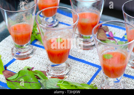 Zuppa Gazpacho in bicchieri sul blu e tovaglia bianca Foto Stock