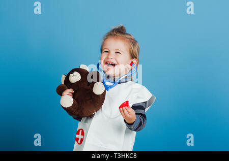 Bambino felice veterinario sorriso con Teddy bear su sfondo blu Foto Stock