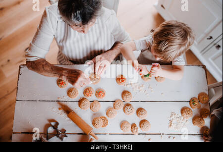 Una vista in pianta della nonna senior con piccole toddler boy fare torte a casa. Foto Stock