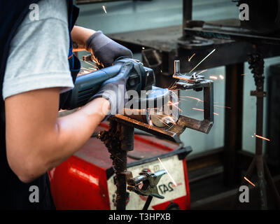 L'uso della smerigliatrice angolare in una lamiera di fabbrica. Foto Stock