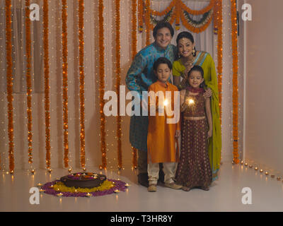 Ritratto di una famiglia indiana di quattro CELEBRA LA FESTA DI DIWALI NELLA LORO CASA Foto Stock