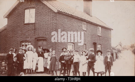 Vintage Edwardian Cartolina fotografica che mostra un grande gruppo di ragazzi e ragazze insieme in un Villaggio Inglese. Foto Stock