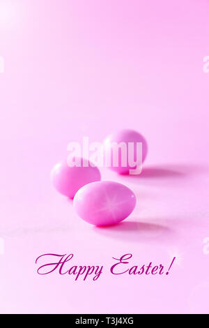 Tre piccole uova rosa su sfondo rosa. Celebrare la Pasqua concetto. Copia dello spazio. Foto Stock