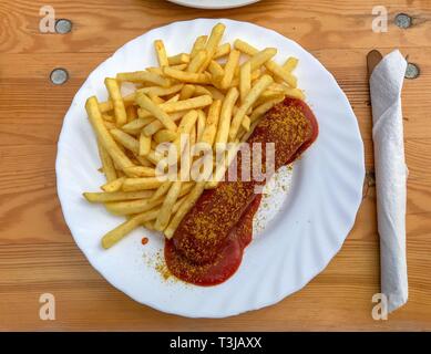 Berlino originale salsiccia al curry, patatine fritte, posate, igienico, tavolo in legno, Berlino, Germania Foto Stock