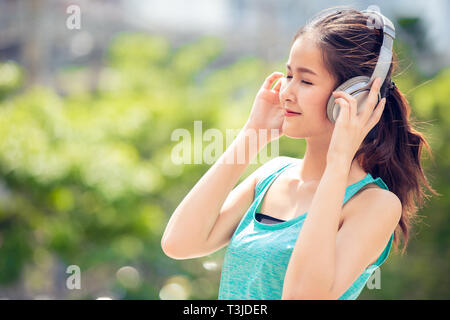 Teen con cuffie wireless sorridente ascoltare musica all'aperto Foto Stock