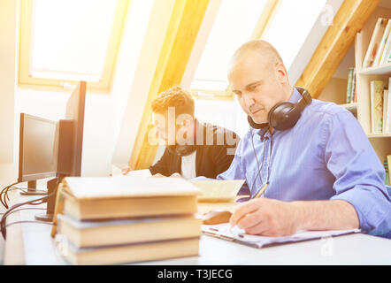 L uomo mentre studiava per esami a un posto di lavoro in una libreria Foto Stock