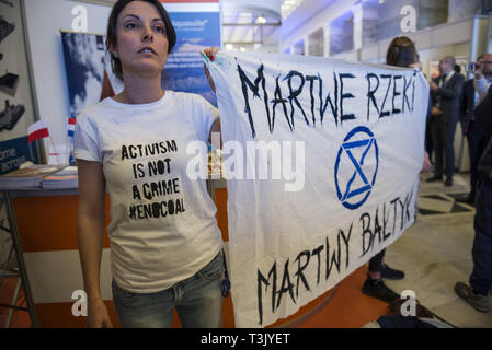 Varsavia, Mazowieckie, Polonia. Decimo Apr, 2019. Un attivista visto indossare una t-shirt dicendo attivismo non è un crimine e tenendo un banner durante la mostra e la conferenza. Durante l'acqua Expo Polonia Salone Internazionale e Conferenza, un gruppo di attivisti ecologici dalla ribellione di estinzione inaspettatamente asportata per evidenziare quanto sia pericoloso per l'ambiente è la costruzione di canali e vie navigabili fluviali. Acqua Expo è la Polonia è solo per esposizioni e conferenze per eventi completamente coprono tutti gli aspetti degli investimenti legati alle acque interne. (Credito Immagine: © Attila Husejnow/SOPA Imag Foto Stock