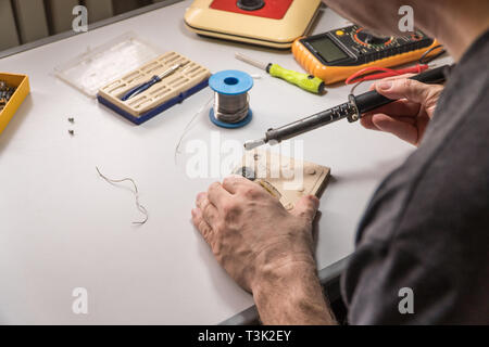 Il tecnico elettricista prepara rosin saldatoio per lavoro Foto Stock