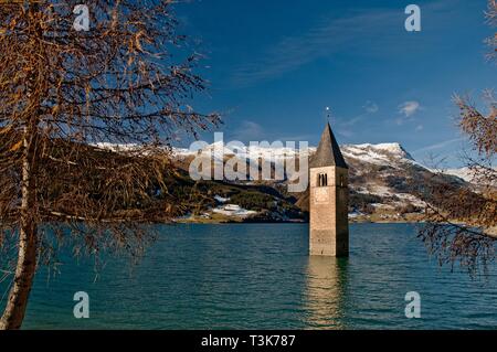 Il campanile della chiesa della ex chiesa parrocchiale Sankt Katahrina di Graun in Reschensee, sullo sfondo il Piz Lad, Val Venosta, Alto Adige, Italia Foto Stock