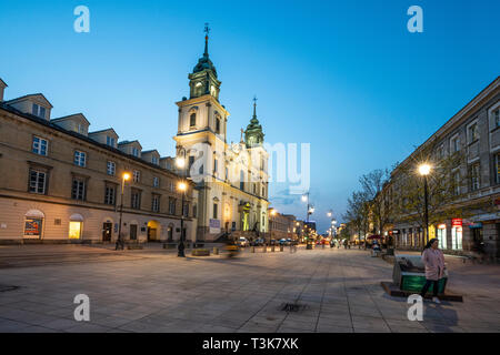 Varsavia, Polonia. Il 6 aprile 2019. Una vista della chiesa di Santa Croce di Krakowskie Przedmieście street al tramonto Foto Stock