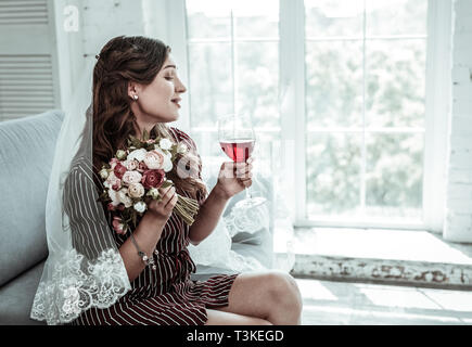 Donna che indossa un velo di nozze bere il vino Foto Stock