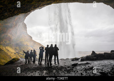 Seljalandsfoss cascata, turisti sta immagine sotto la cascata Foto Stock