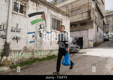 Un ragazzo palestinese costeggia la resistenza dipinti sui muri di Aida Camp, Betlemme, West Bank, Palestina, 11/02/19 Foto Stock